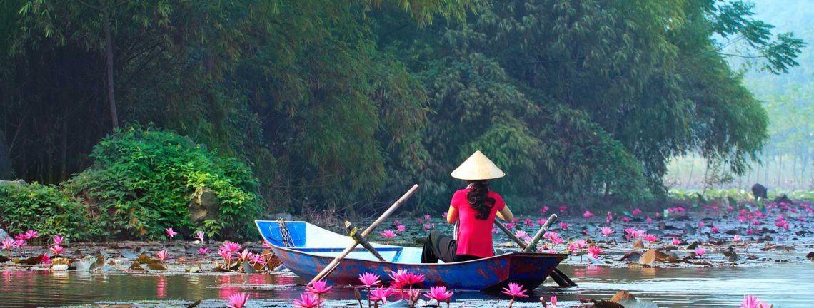 Femme en barque sur lac au nénuphars au Vietnam